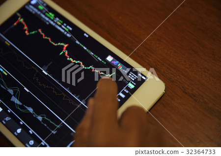 A hand Trading online on tablet with business paper and coffee A hand Trading online on tablet with business paper and coffee 32364733