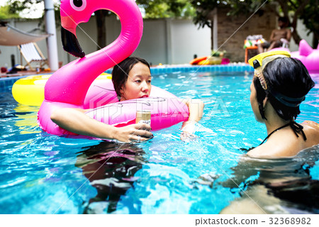 Asian women enjoying the pool with inflatable tubes Asian women enjoying the pool with inflatable tubes 32368982