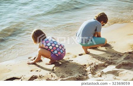 Little children playing sand by the seashore Little children playing sand by the seashore 32369059
