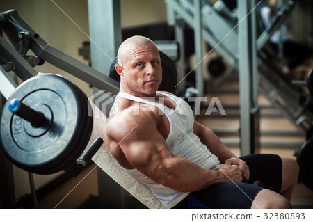 Bodybuilder sits on a simulator 32380893