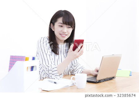 A young woman desking with a smartphone and a computer 32385674