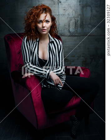 Curly woman siting on red chair Curly woman siting on red chair 32389127
