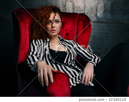 Curly woman siting on red chair Curly woman siting on red chair 32389128