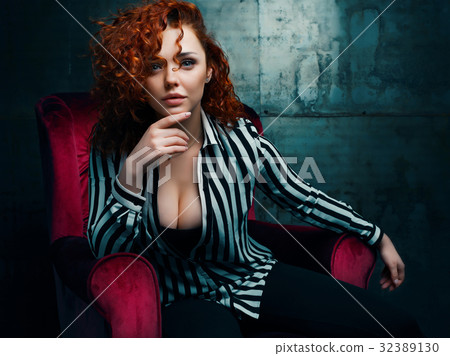 Curly woman siting on red chair Curly woman siting on red chair 32389130