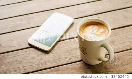 Hot latte coffee and smartphone on a wooden table. 32402443