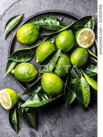 Green lemon Lime with fresh leaves on black plate 32408566