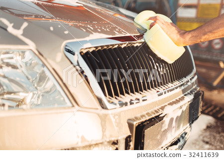 Male hand rubbing the car with foam, carwash 32411639