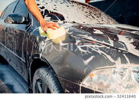 Male hand rubbing the car with foam, carwash 32411640