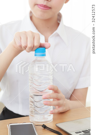 A young woman in an office opening a lid of hydration supplement PET bottle 32412573