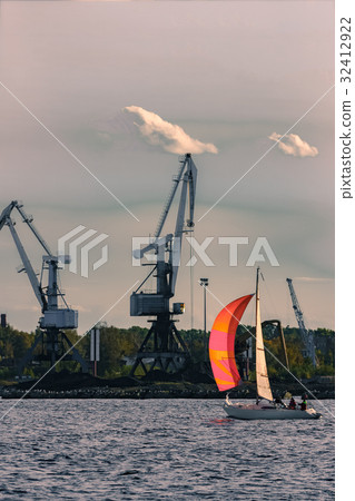 Sailboat moving past the cargo cranes 32412922