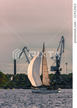 Sailboat moving past the cargo cranes 32412923