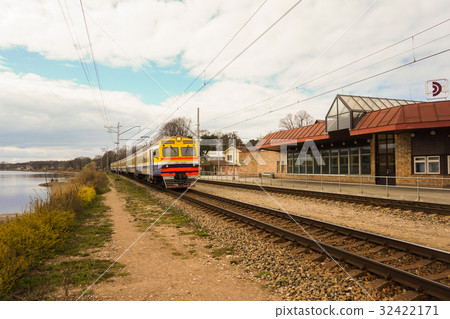 Suburban train arrives at the station near lake 32422171