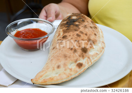 Pizza calzone served on a white plat Pizza calzone served on a white plat 32426186