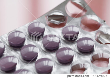 Close-up of purple pills in a pack on a pink Close-up of purple pills in a pack on a pink 32429024