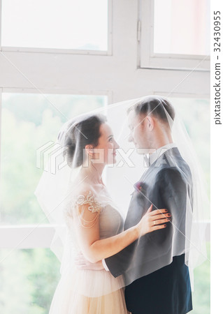 Beautiful bride and groom with veil over face Beautiful bride and groom with veil over face 32430955