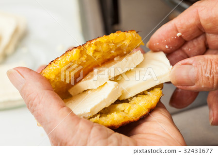 Stuffing the cooked arepa with cheese 32431677