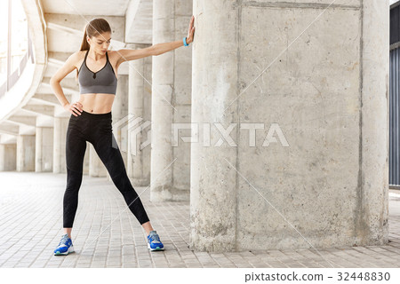 Serious female athlete warming up in stadium Serious female athlete warming up in stadium 32448830