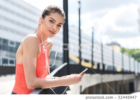 Cheerful sporty girl using smartphone player after Cheerful sporty girl using smartphone player after 32448947