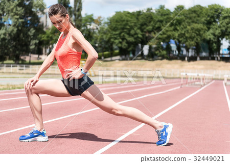 Serious female runner doing preparatory exercises 32449021