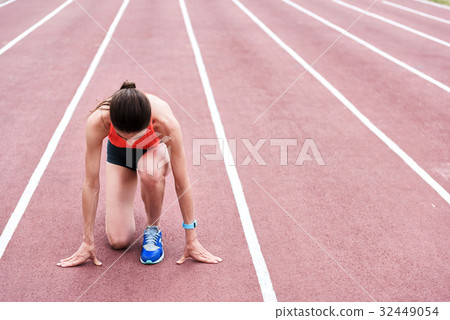 Concentrated female runner standing at starting 32449054