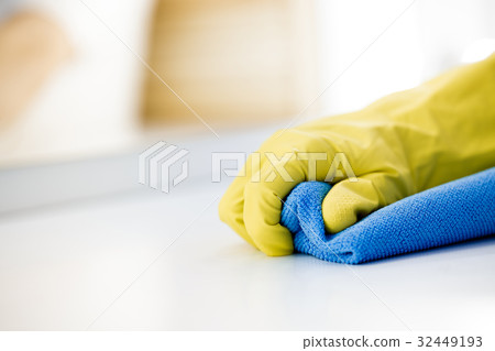 Female hand in rubber yellow glove cleans surface 32449193