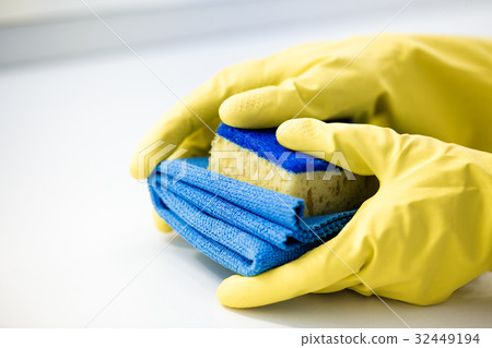 hand  in a rubber yellow glove holding sponge.  32449194