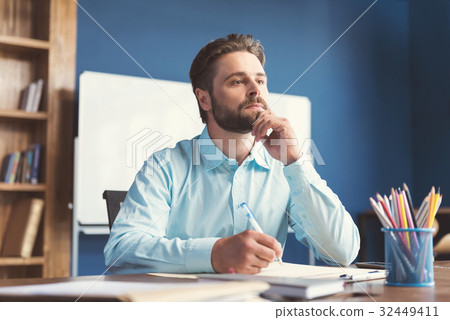 Thoughtful youthful bearded guy doing test for job Thoughtful youthful bearded guy doing test for job 32449411