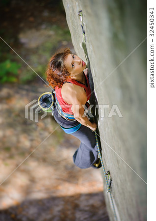 Beautiful woman climber climbing steep rock with rope Beautiful woman climber climbing steep rock with rope 32450341