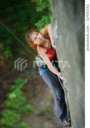 Beautiful woman climber climbing steep rock with rope Beautiful woman climber climbing steep rock with rope 32450342