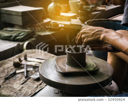 potter shaping soft clay to make an earthen pot 32450924