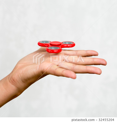Red hand spinner. Boy playing a popular toy fidget Red hand spinner. Boy playing a popular toy fidget 32455204