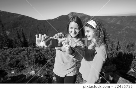 Two happy female hikers smiling and taking selfie photo Two happy female hikers smiling and taking selfie photo 32455755