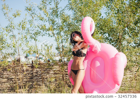 woman holding pink inflatable flamingo float 20s 32457336