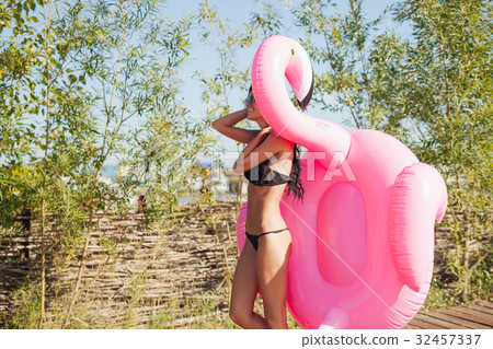 woman holding pink inflatable flamingo float 20s 32457337