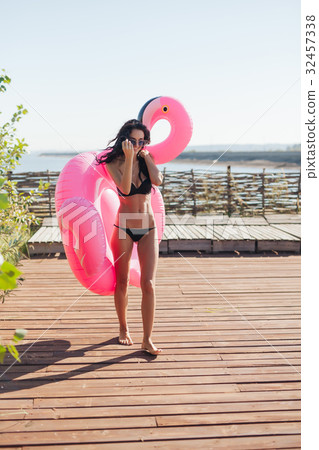 woman holding pink inflatable flamingo float 20s woman holding pink inflatable flamingo float 20s 32457338