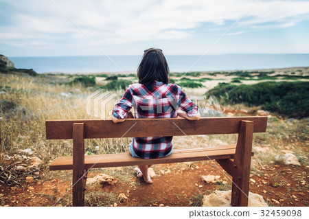 Woman enjoying sea view sitting on a bench in beautiful valley Woman enjoying sea view sitting on a bench in beautiful valley 32459098