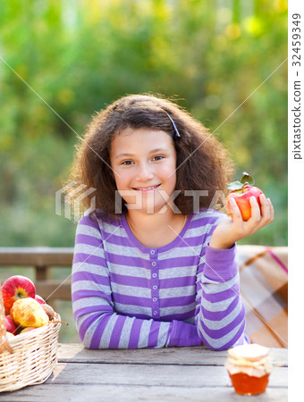 Smiling little girl with basket of red apples 32459349
