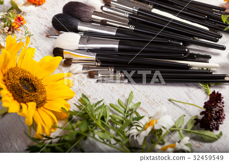 Make up brushes on a table next to wild flowers Make up brushes on a table next to wild flowers 32459549