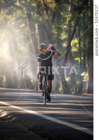 Cyclist drinking from a bottle while riding  32470237