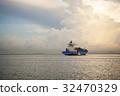 Cargo ship sailing away against sunrise 32470329