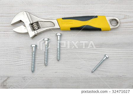 A yellow wrench and four screw bolts placed on 32471027