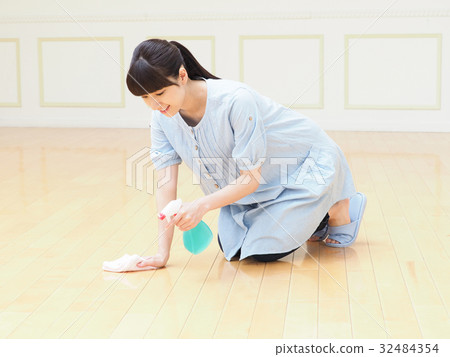 A woman cleaning a floor with a smile 32484354