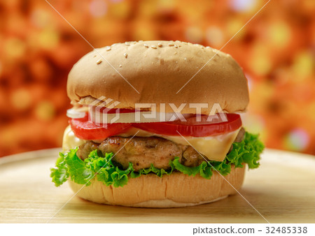 Burger on wooden plate with orange background Burger on wooden plate with orange background 32485338