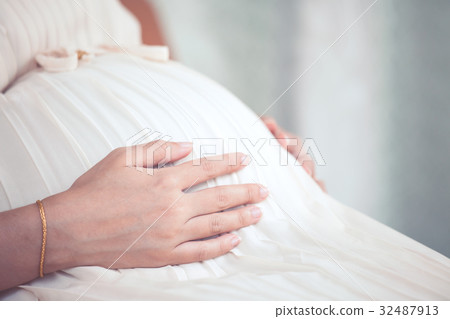 Pregnant woman sitting and touching her big belly 32487913