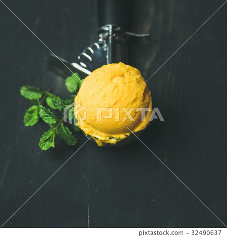 Mango sorbet ice cream scoop in scooper, square Mango sorbet ice cream scoop in scooper, square 32490637