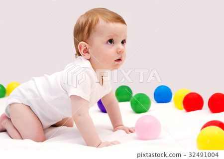 Funny baby boy playing with colorfull balls on the Funny baby boy playing with colorfull balls on the 32491004