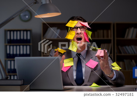 Businessman staying late to sort out priorities Businessman staying late to sort out priorities 32497181