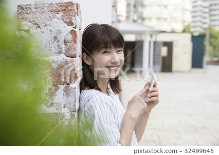A young woman operating a smartphone 32499648