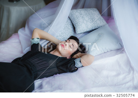 Pretty brunette woman lies on bed 32505774