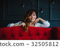 pretty brunette young woman posing behind red sofa 32505812